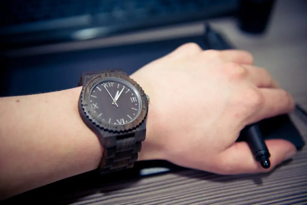 man workin on a computer with wooden watch on wrist