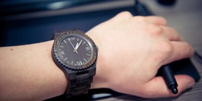 man workin on a computer with wooden watch on wrist