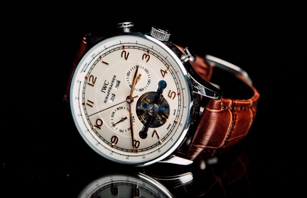 A white-dial watch with movement visible through a cut