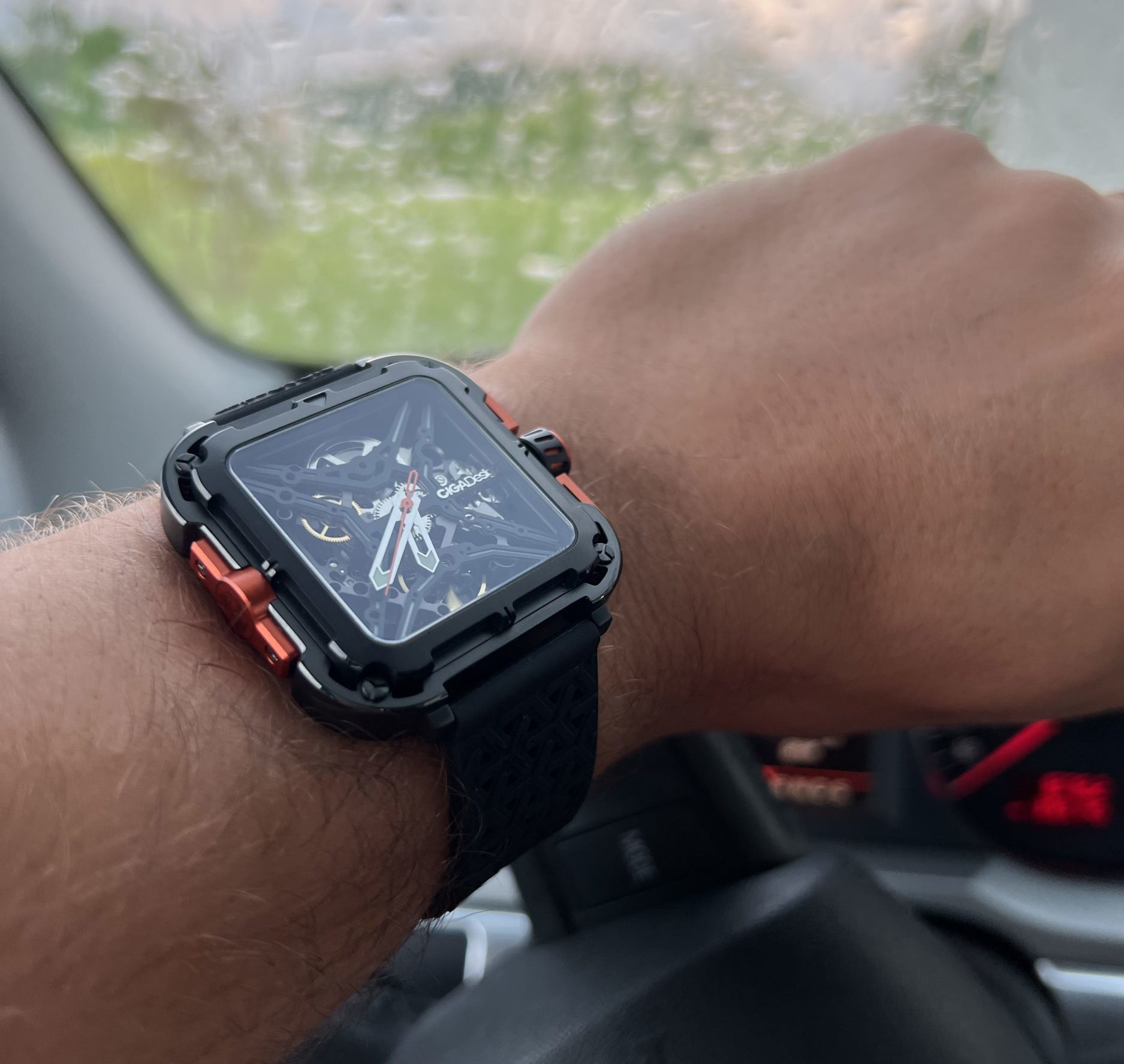 Extravagant timepiece on a wrist behind the car wheel