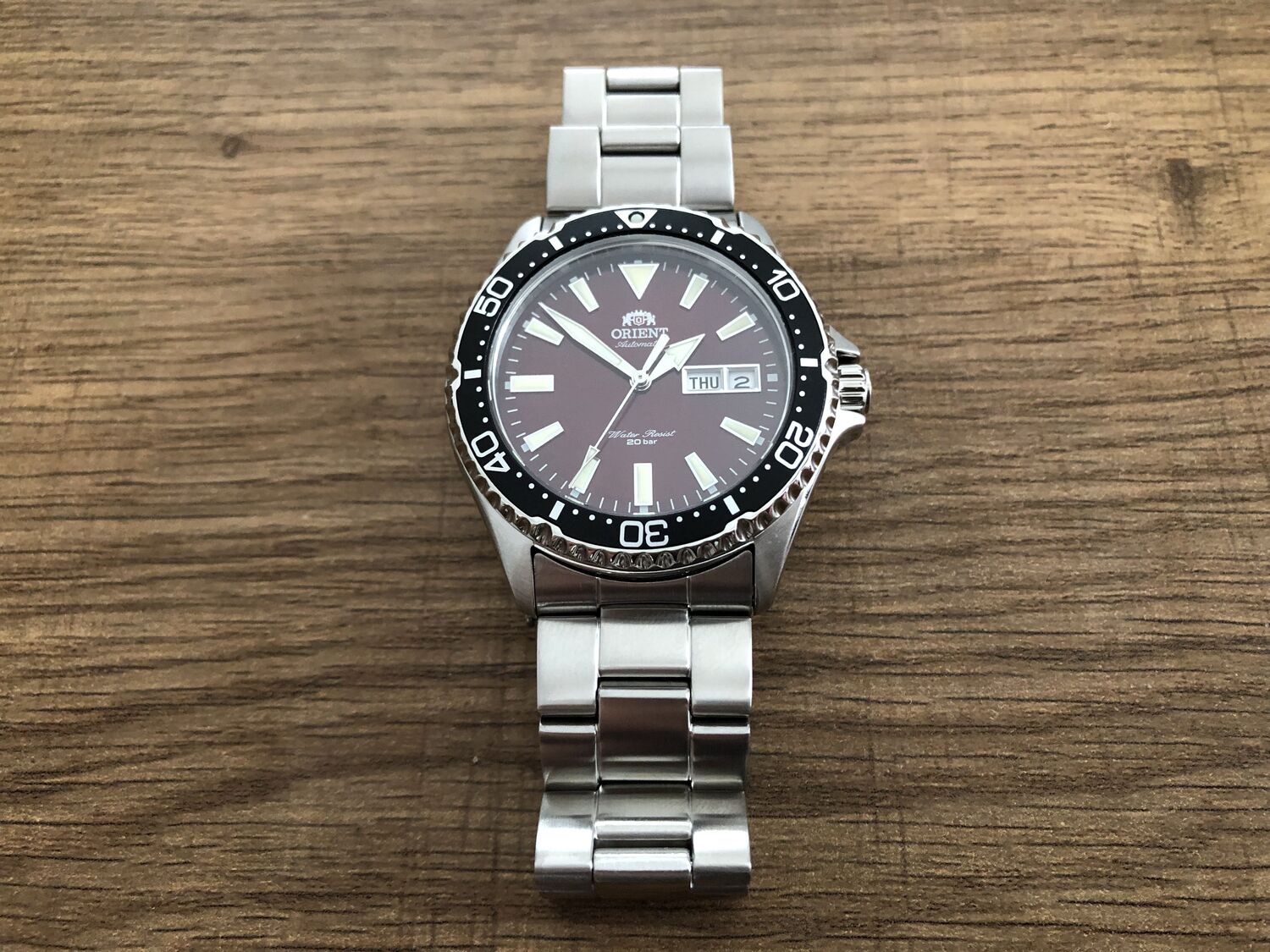 A red-dialed dive watch on a brown wooden table